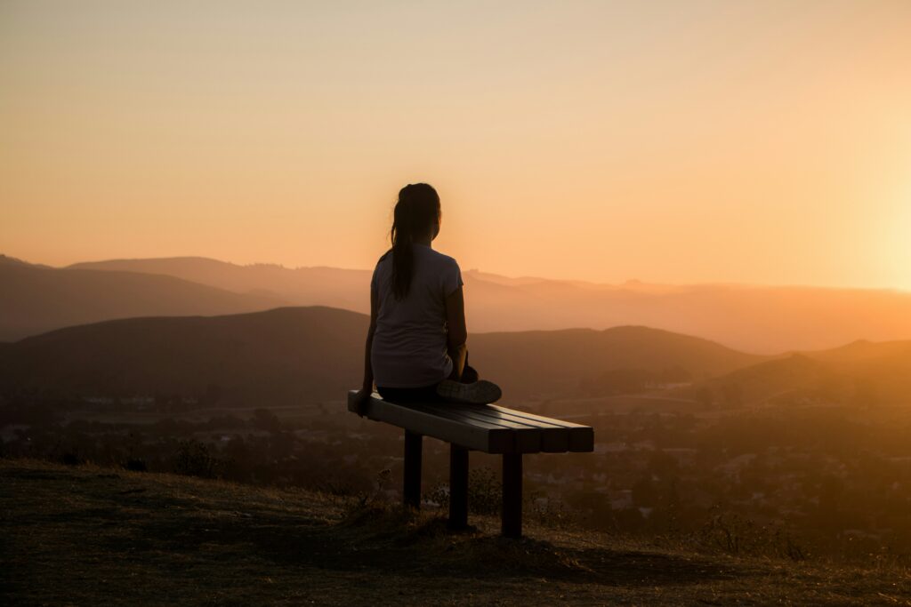 Réflexologie plantaire – Retrouver calme et équilibre Femme assise face au paysage dans un moment de calme et de détente
