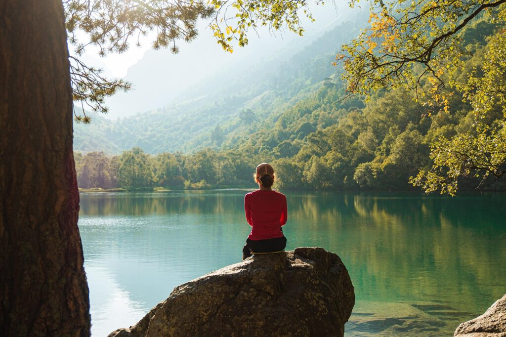 Les bénéfices de la sophrologie – Sérénité et équilibre Personne assise au bord d’un lac dans un environnement calme et naturel